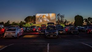cars in front of a big screen at night